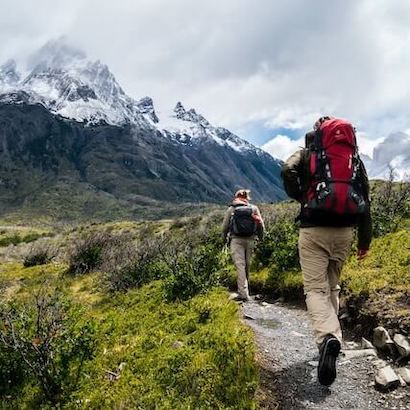 Two hikers walking together along a mountain trail.