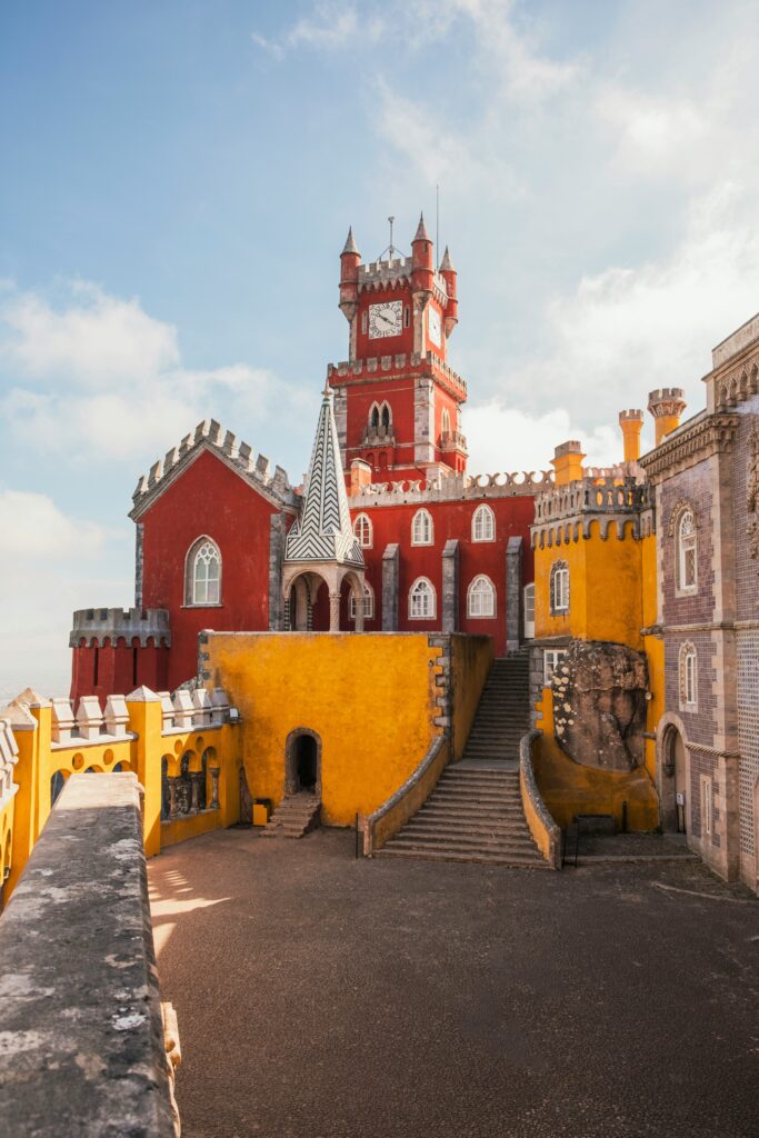 Sintra Palace in Portugal with vibrant red and yellow hues on a sunny day, showcasing intricate architectural details.