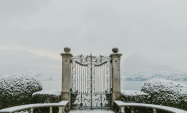 Gate at Parco Ciani, overlooking Lake Lugano with snow-capped mountains in the distance.