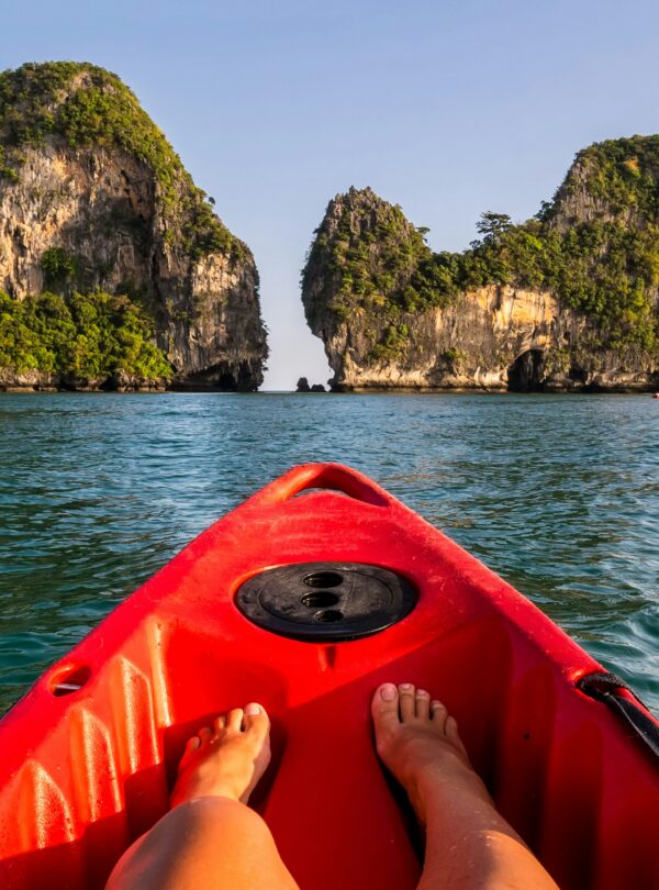 Person paddling a canoe on a calm lake surrounded by lush nature, symbolizing the connection between sports and the outdoors.